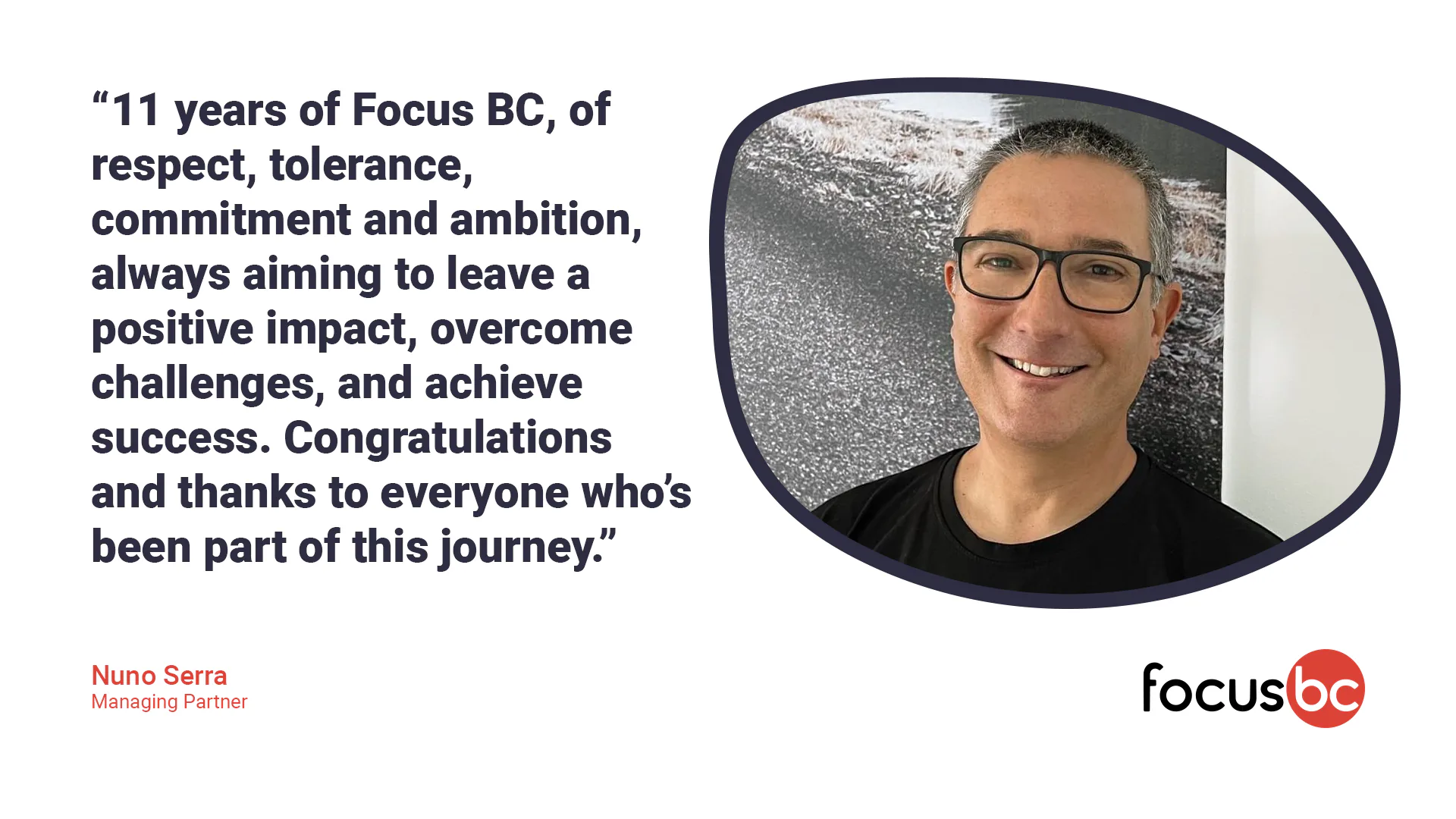 Large group of colleagues seated around a long restaurant table enjoying dinner together and smiling toward the camera.