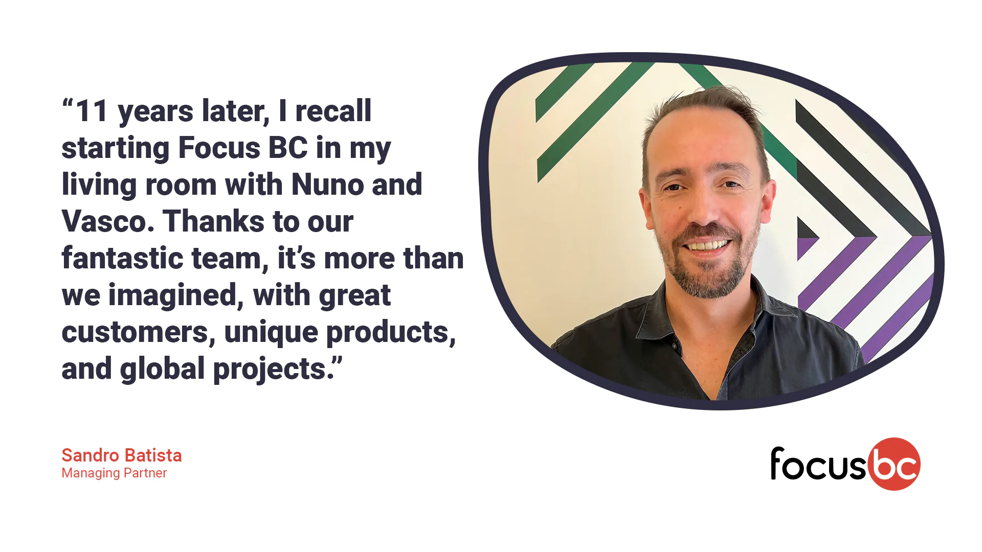 Large group of colleagues seated around a long restaurant table enjoying dinner together and smiling toward the camera.