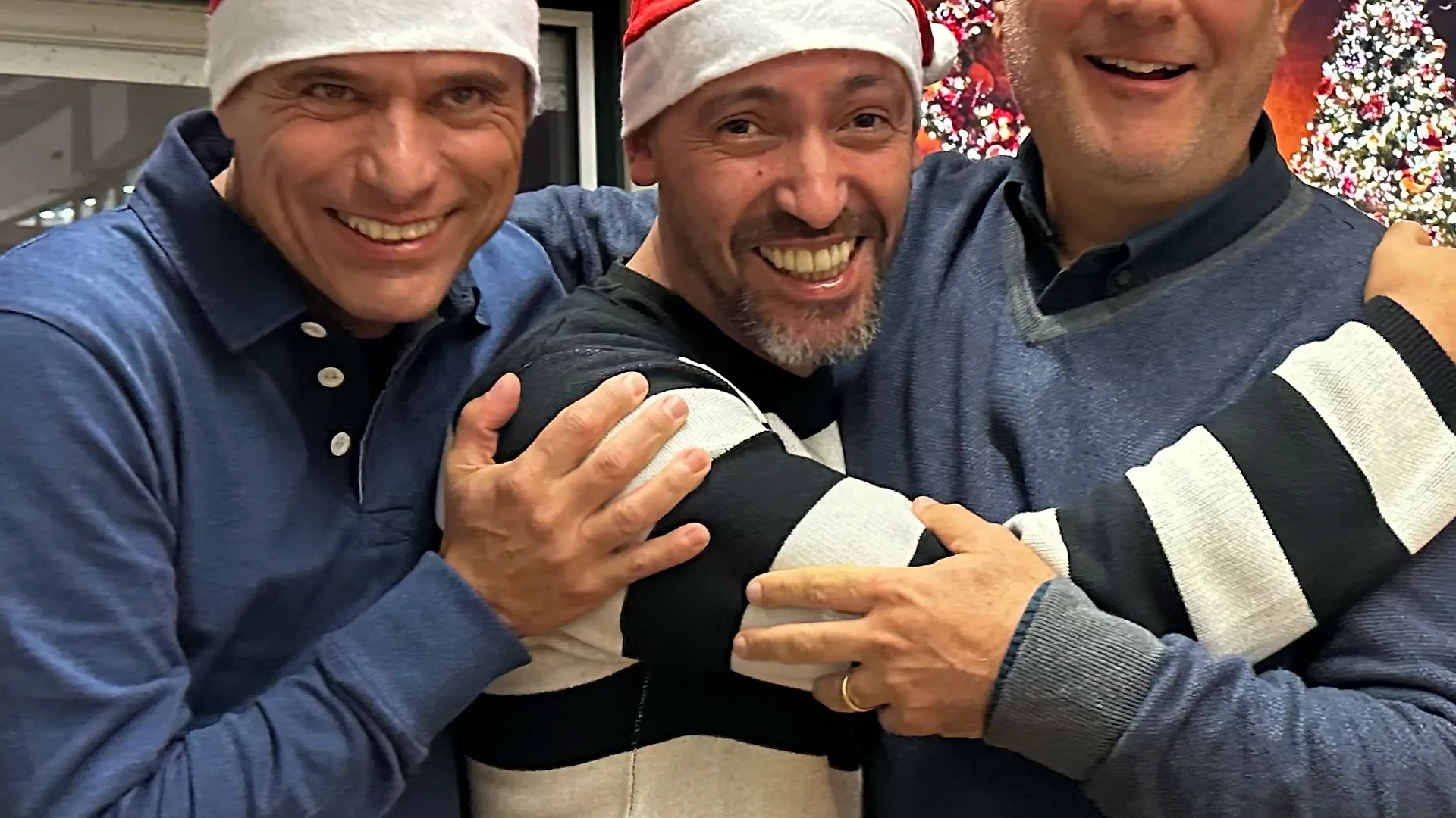 Founders with Santa hats and holiday glasses stand arm in arm, smiling at the camera during a Christmas celebration.