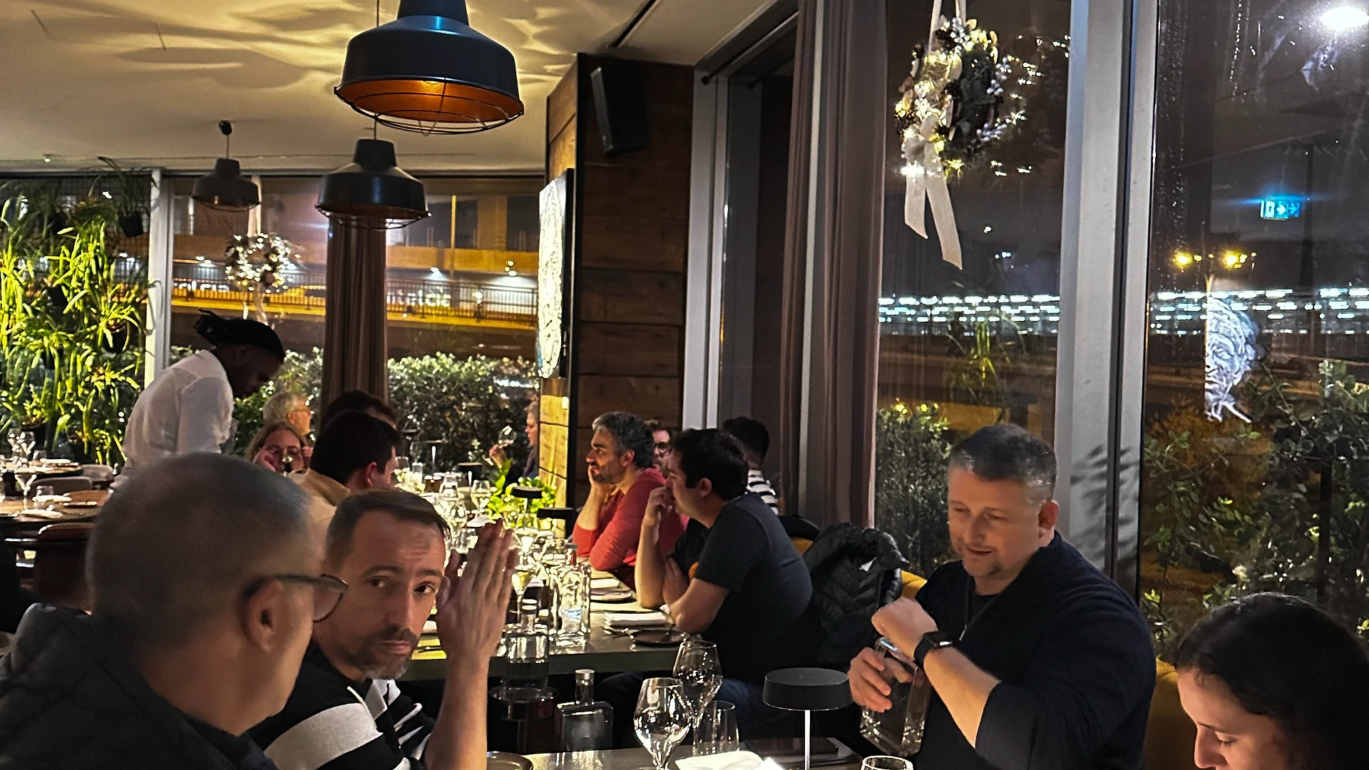 Three team members chatting and smiling, one speaking animatedly while holding a drink.