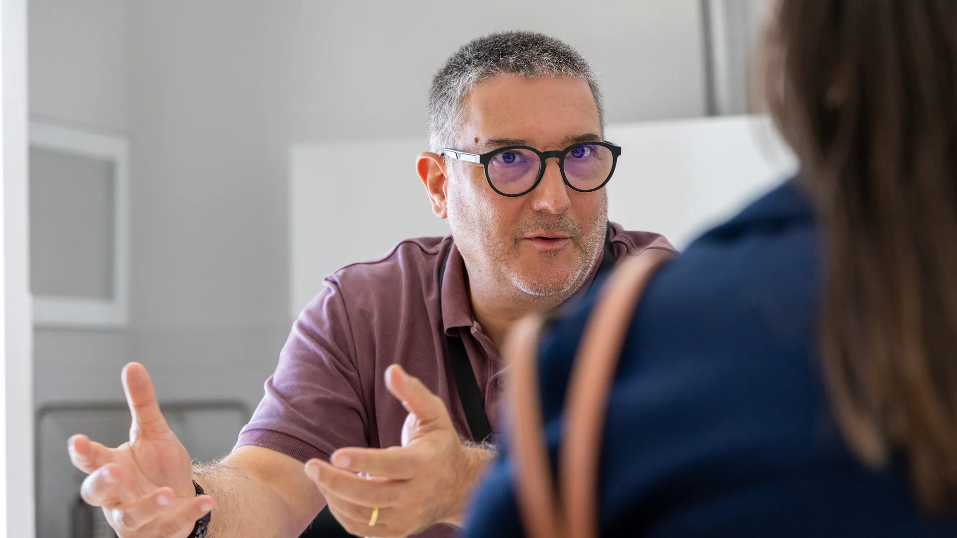 Mario Sobral speaks to a small group of Junitec members, including two young women and a young man, in a casual setting. The participants listen attentively, holding water bottles.