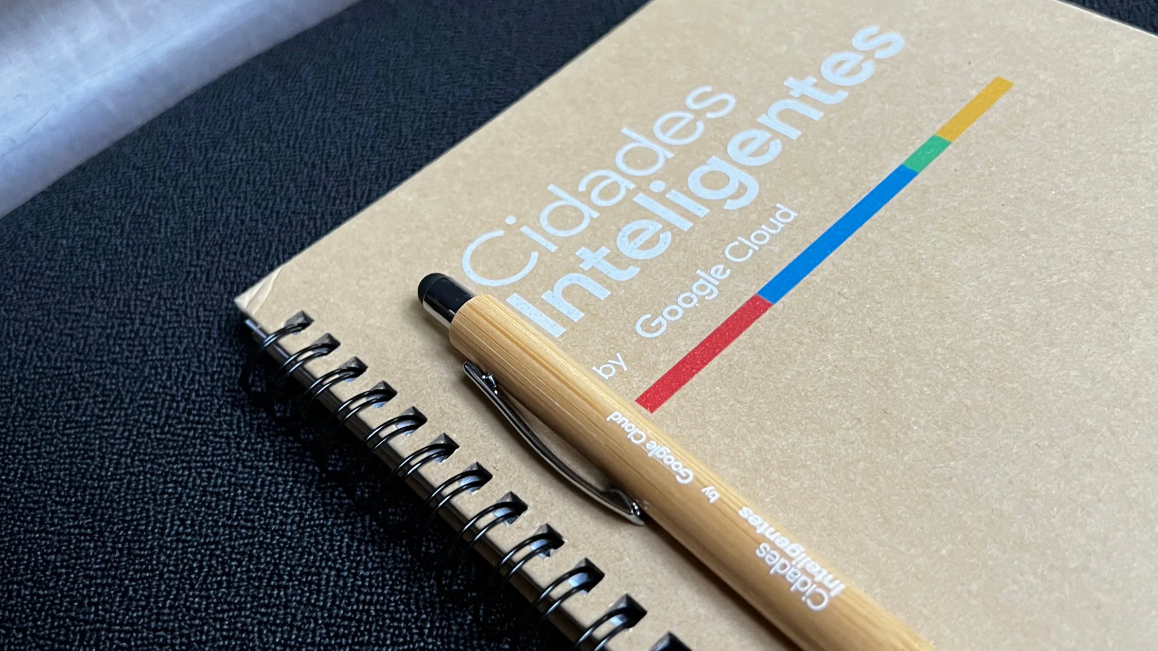 Close-up of a “Cidades Inteligentes by Google Cloud” notebook with a wooden pen placed on top.