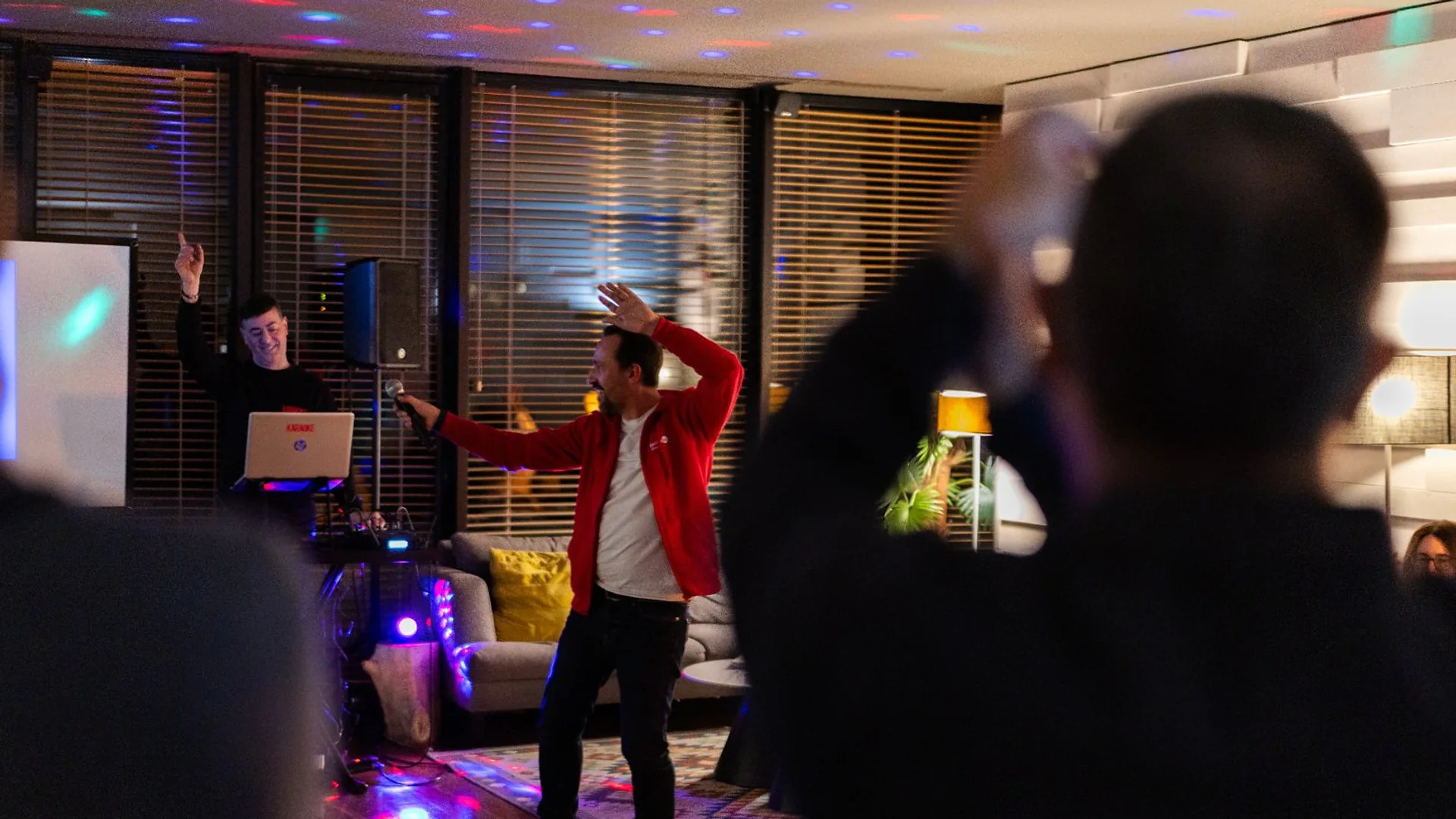 Audience members seated at a table applauding during a presentation, with water bottles and glasses on the table.