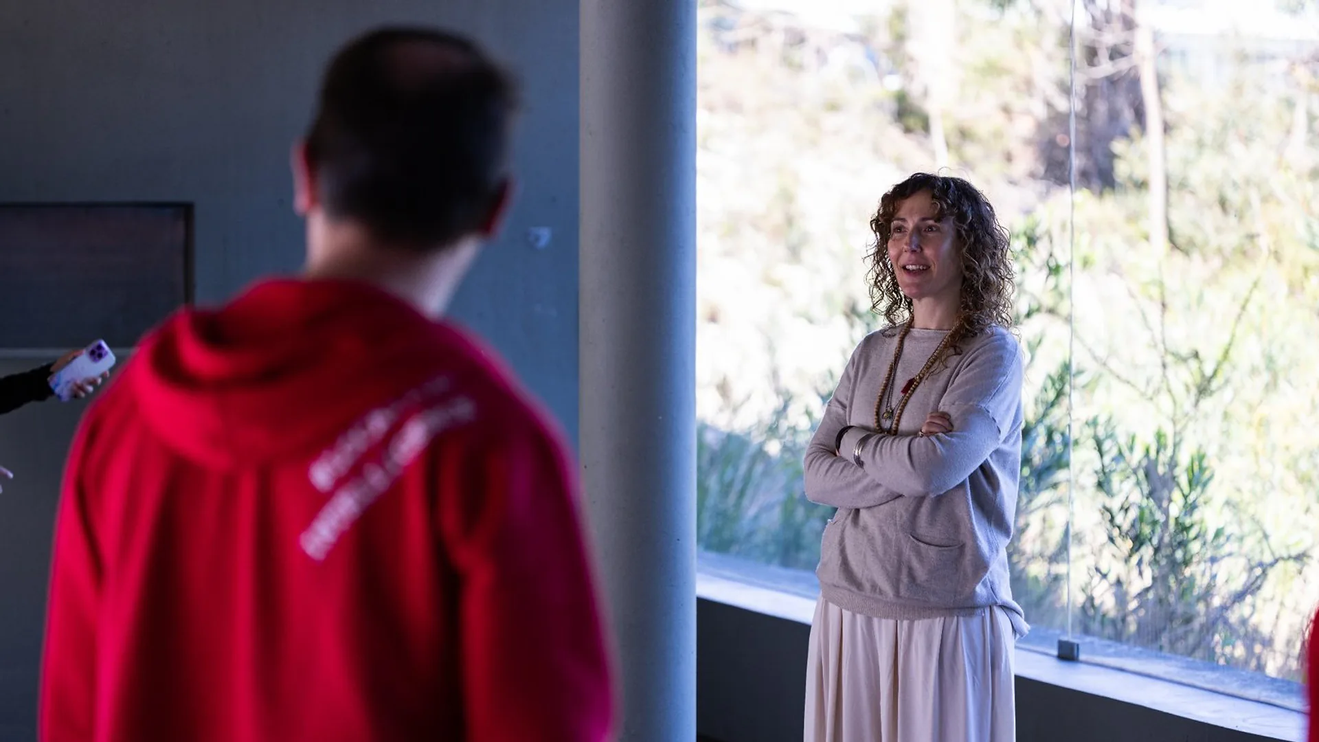 Audience members seated at a table applauding during a presentation, with water bottles and glasses on the table.