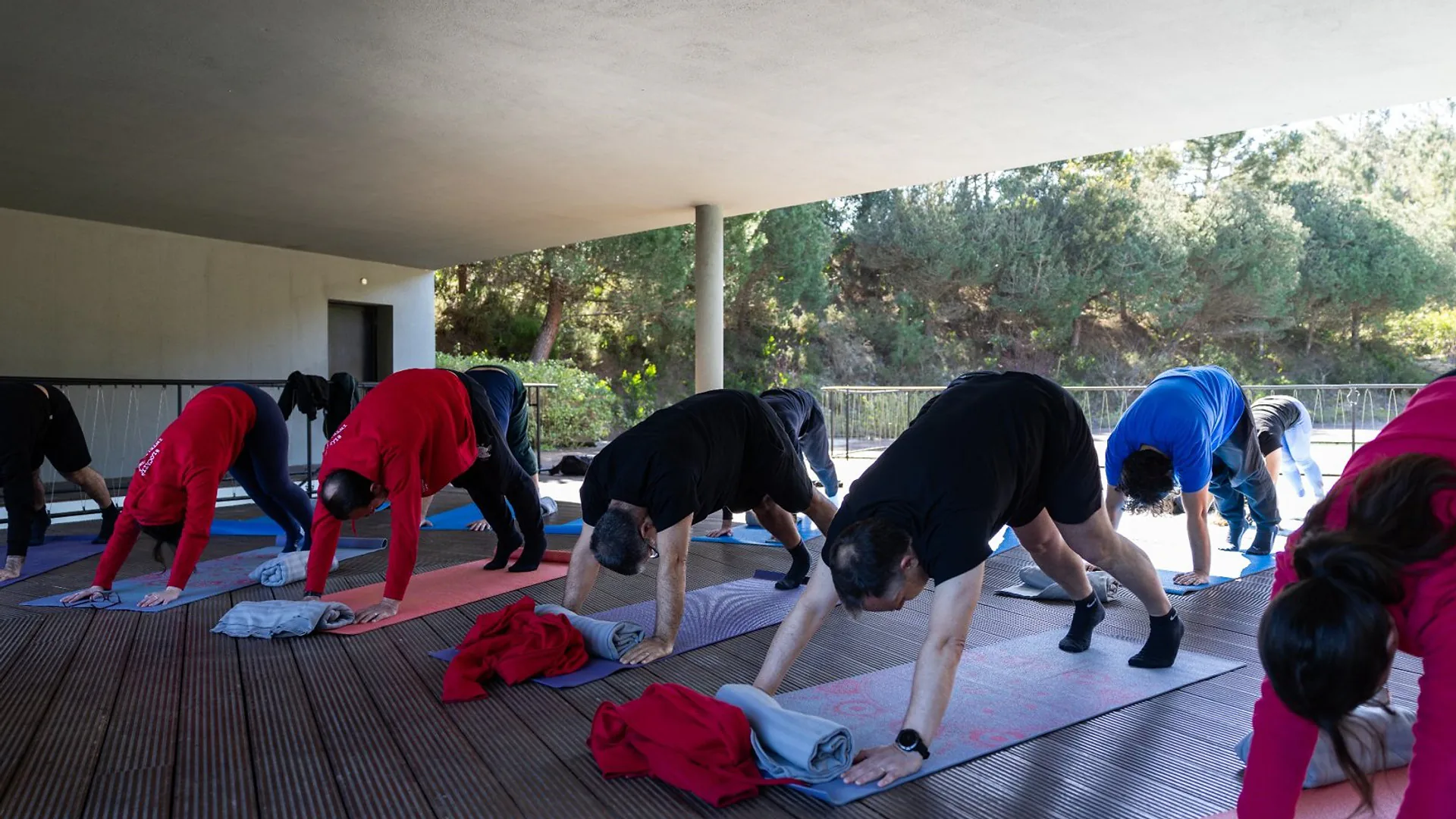 Man standing near a screen during a presentation, resting his hand near his face while listening.