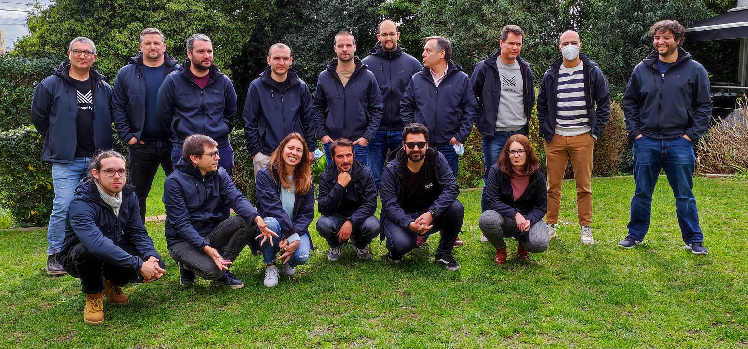Focus BC team group photo outdoors on a lawn, with members standing and crouching together in matching dark jackets.