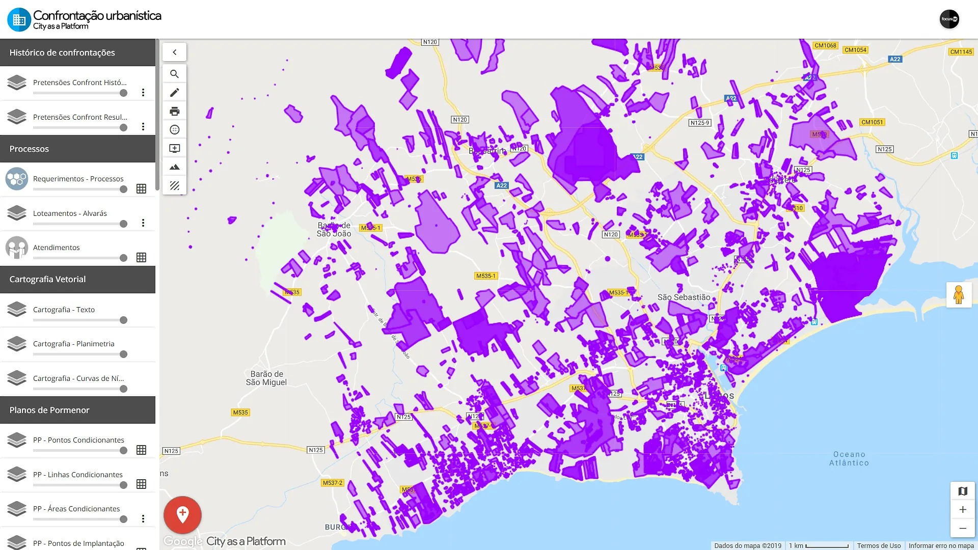 Two professionals discussing solutions at the Focus BC “Gestão urbanística” booth with a screen displaying a city management platform.
