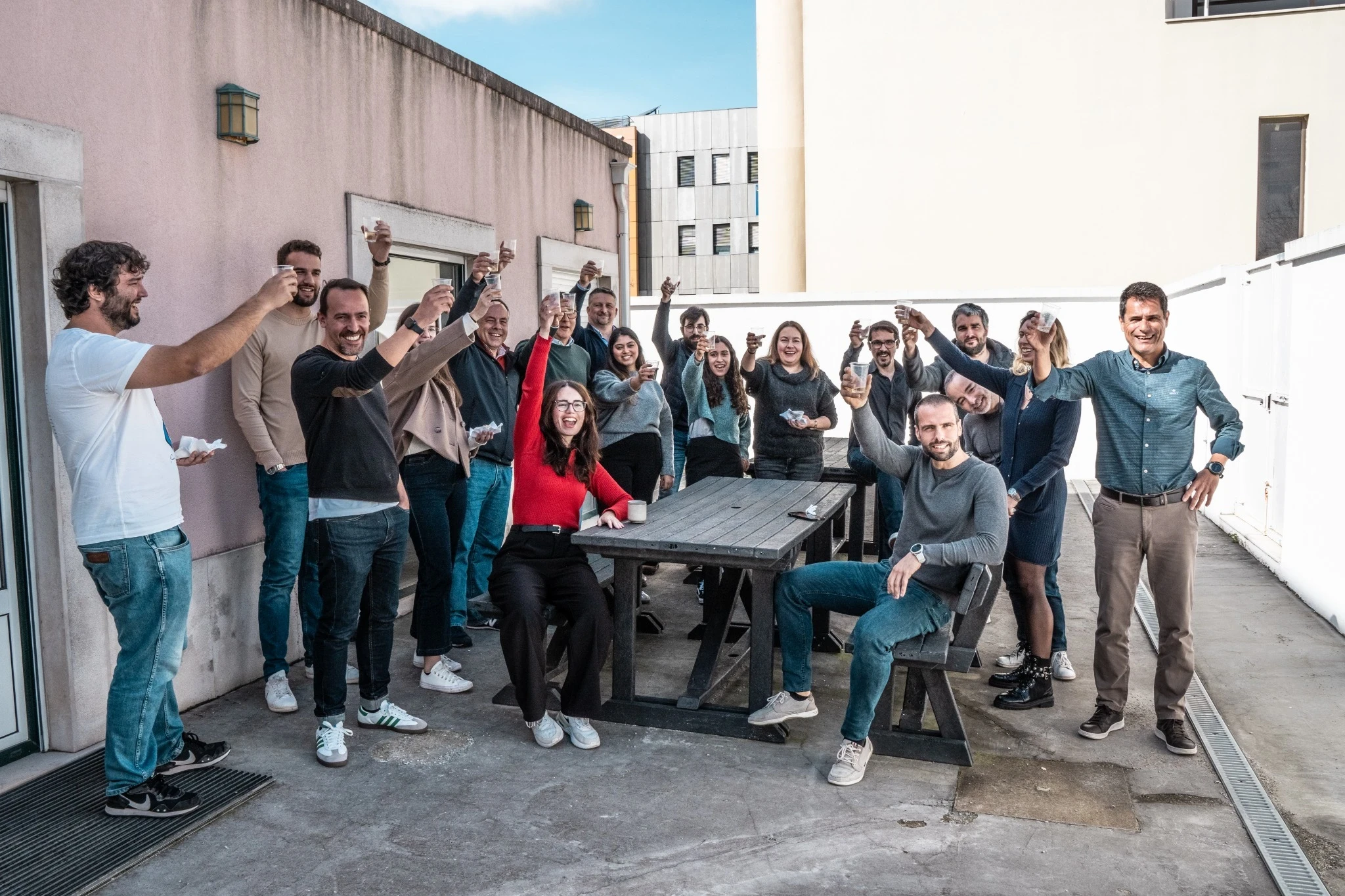 Team members seated at a table applauding and smiling during a meeting or presentation, with notebooks and water glasses in front of them.